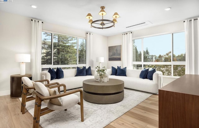 living room with light hardwood / wood-style floors and a notable chandelier