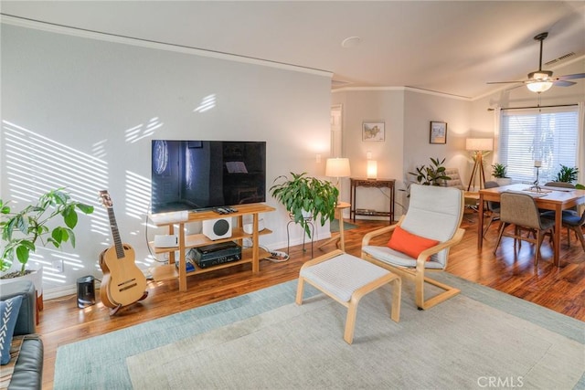 living room featuring ceiling fan, ornamental molding, and hardwood / wood-style floors