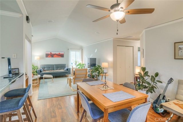 dining area with ceiling fan, vaulted ceiling, ornamental molding, and light hardwood / wood-style flooring