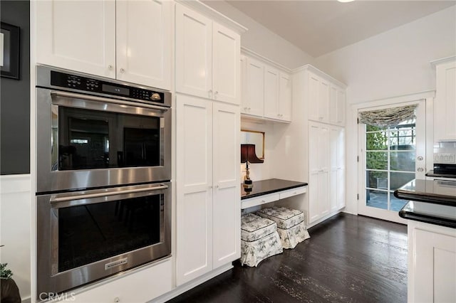 kitchen with dark wood-type flooring, white cabinets, and stainless steel double oven