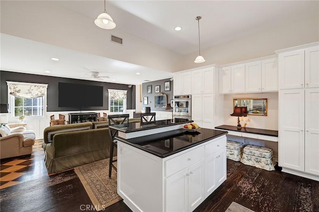 kitchen with ceiling fan, white cabinetry, and hanging light fixtures