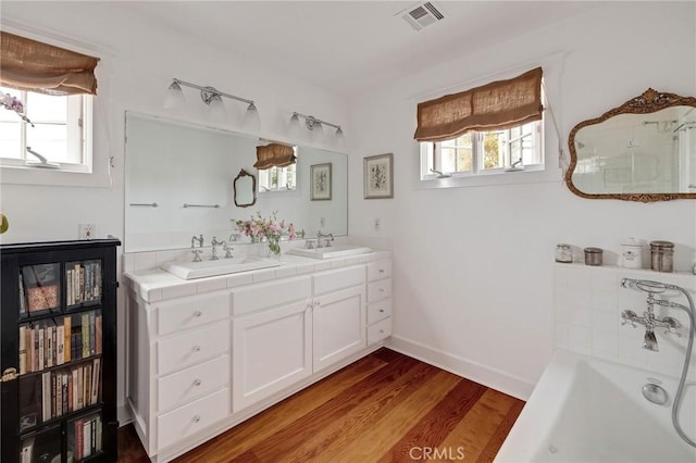 bathroom with a bathing tub, hardwood / wood-style floors, and vanity