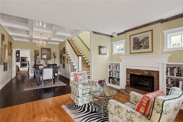 living room featuring a healthy amount of sunlight, wood-type flooring, a fireplace, and coffered ceiling