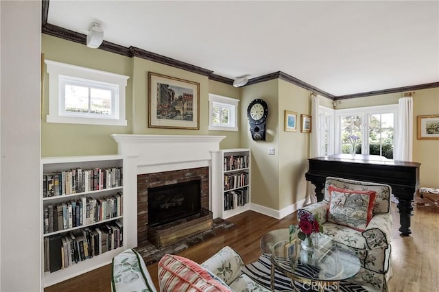 living area featuring built in features, dark hardwood / wood-style flooring, crown molding, and a fireplace