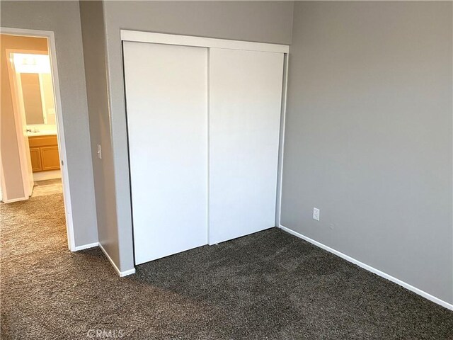 unfurnished bedroom with a closet and dark carpet