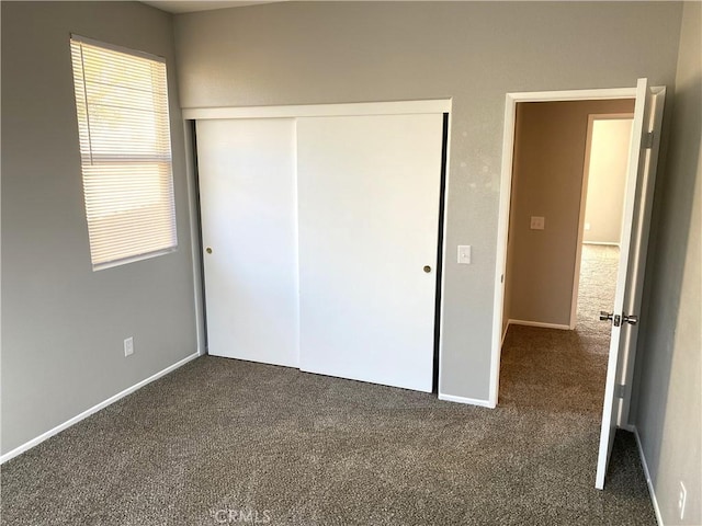 unfurnished bedroom featuring dark carpet and a closet