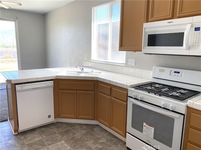 kitchen featuring tile countertops, kitchen peninsula, sink, and white appliances