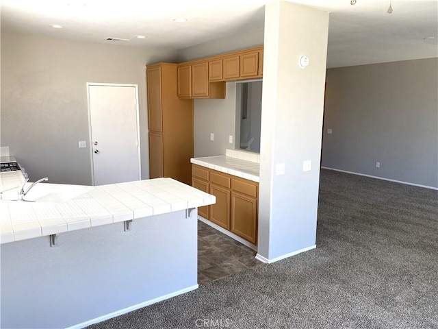 kitchen featuring sink, a kitchen breakfast bar, tile countertops, and dark carpet