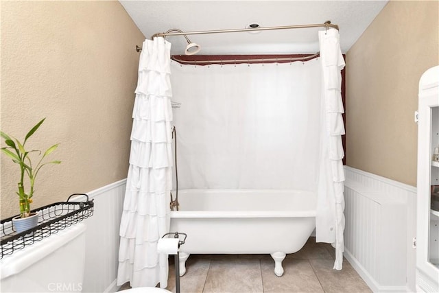 bathroom featuring toilet, tile patterned floors, and shower / tub combo with curtain