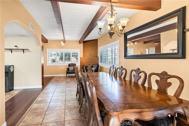 dining room featuring tile patterned floors, beamed ceiling, and a chandelier