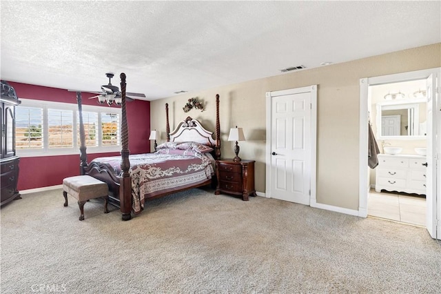 carpeted bedroom with ensuite bath, ceiling fan, and a textured ceiling