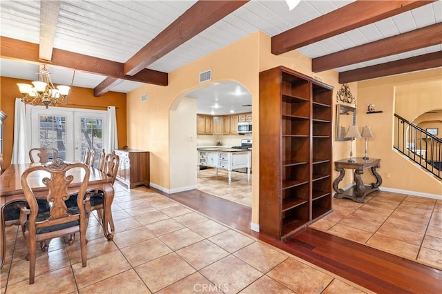 tiled dining space featuring beam ceiling and a chandelier