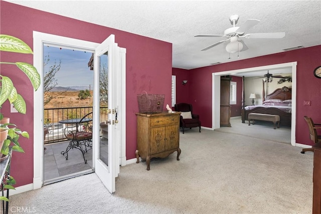 bedroom featuring ceiling fan, access to exterior, a textured ceiling, and light carpet