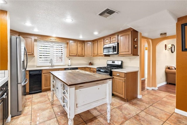 kitchen featuring sink, appliances with stainless steel finishes, a center island, and light tile patterned flooring