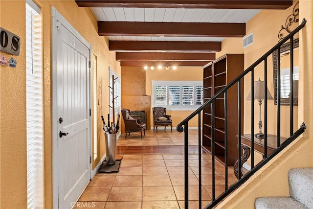 entryway with wooden ceiling, light tile patterned floors, and beamed ceiling