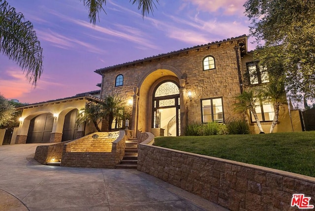 mediterranean / spanish-style home featuring a garage and a lawn