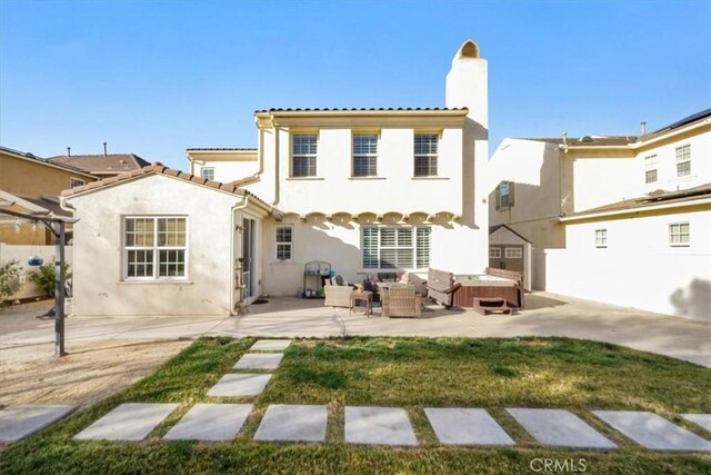 rear view of property featuring a hot tub and a patio