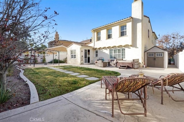 back of property with an outdoor living space, a lawn, a storage unit, and a patio