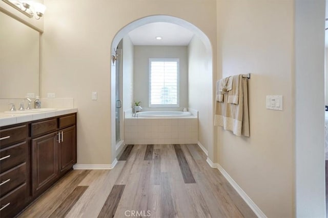 bathroom with hardwood / wood-style floors, vanity, and independent shower and bath