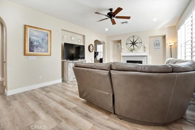 living room with light wood-type flooring, ceiling fan, and plenty of natural light