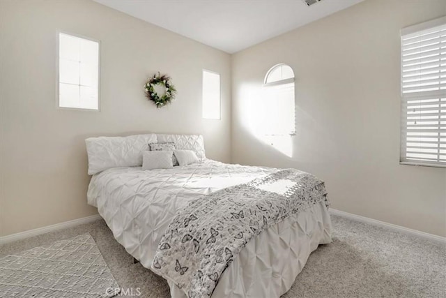 bedroom featuring light colored carpet and multiple windows