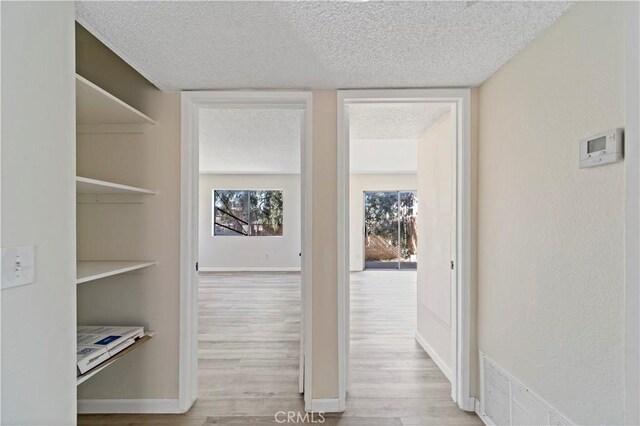 hallway featuring light hardwood / wood-style floors and a textured ceiling