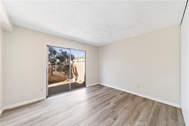 spare room with light hardwood / wood-style floors and a textured ceiling