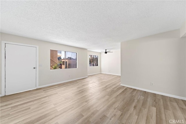 empty room featuring ceiling fan, light wood-type flooring, and a textured ceiling