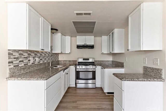 kitchen with white cabinets, dark stone counters, sink, and gas stove