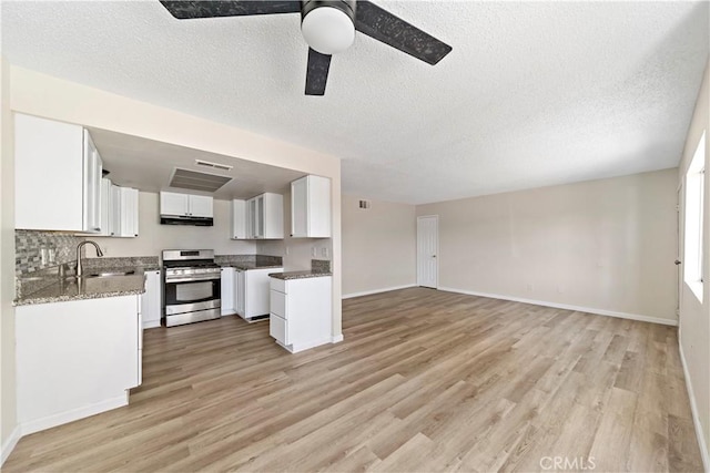 kitchen with white cabinets, stainless steel gas stove, sink, light wood-type flooring, and stone counters