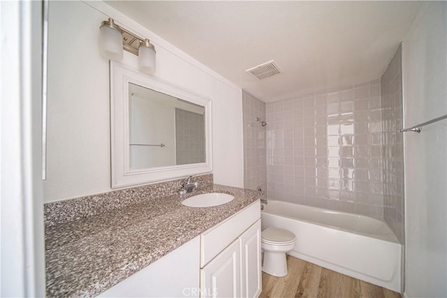 full bathroom featuring hardwood / wood-style floors, toilet, vanity, and tiled shower / bath combo