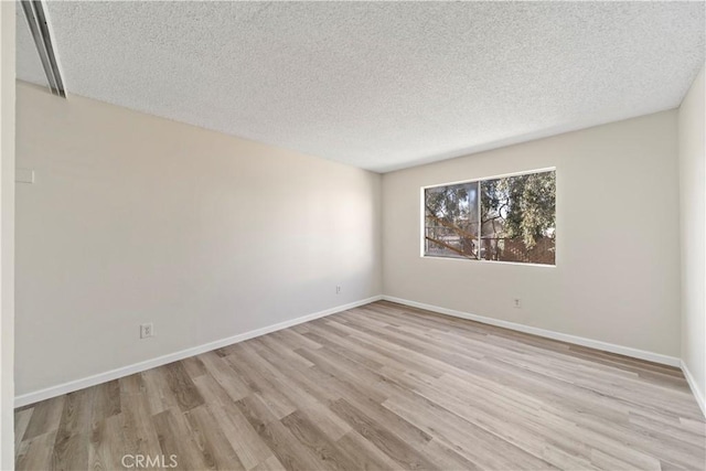 spare room featuring a textured ceiling and light hardwood / wood-style floors