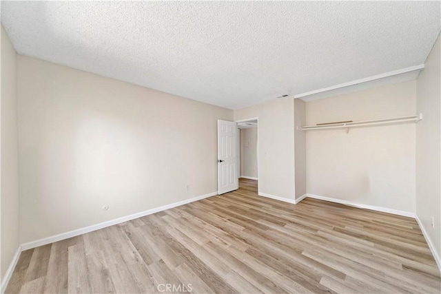 unfurnished bedroom with a textured ceiling, a closet, and light hardwood / wood-style flooring