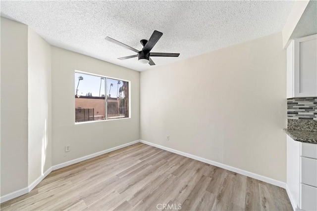 empty room with ceiling fan, a textured ceiling, and light hardwood / wood-style floors