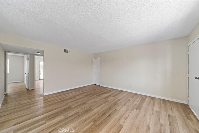 spare room with light wood-type flooring and a textured ceiling