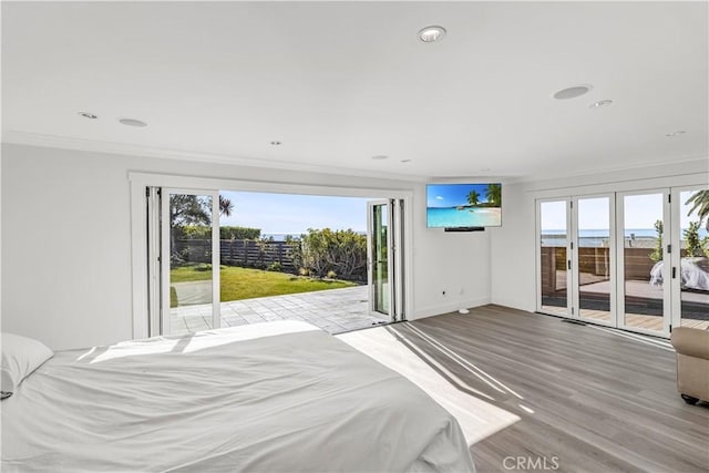 bedroom featuring access to exterior, multiple windows, ornamental molding, and light wood-type flooring