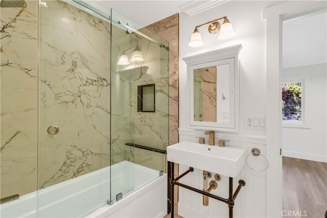 bathroom featuring combined bath / shower with glass door, wood-type flooring, and sink