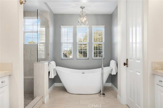 bathroom with plus walk in shower, tile patterned floors, a notable chandelier, and vanity