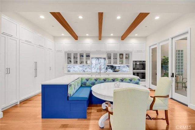 interior space featuring breakfast area, double oven, french doors, backsplash, and a kitchen island