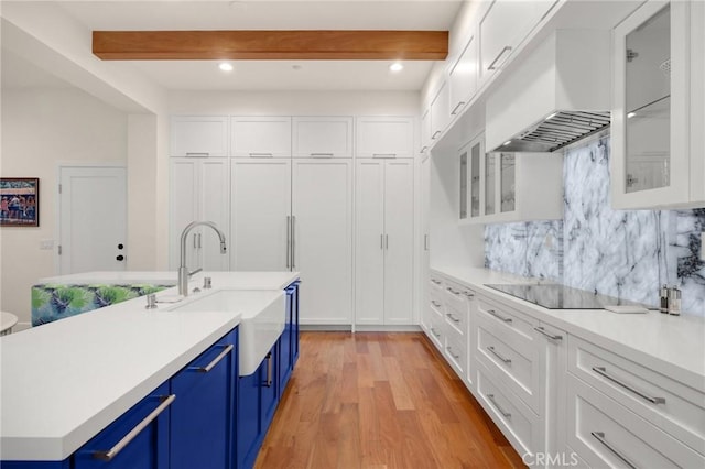 kitchen with white cabinetry, beamed ceiling, blue cabinetry, sink, and custom range hood