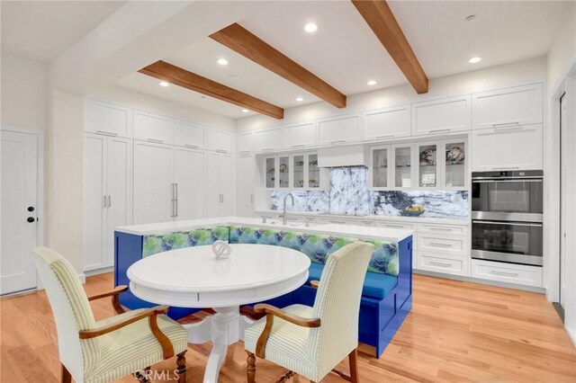 dining area with light hardwood / wood-style floors, sink, breakfast area, and beam ceiling