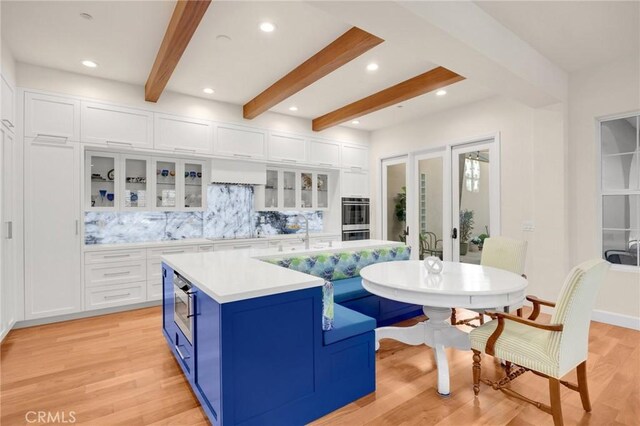 kitchen with white cabinets, a center island, blue cabinetry, and tasteful backsplash