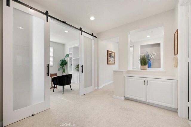 corridor with light colored carpet and a barn door