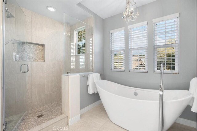 bathroom featuring tile patterned floors, a notable chandelier, and shower with separate bathtub