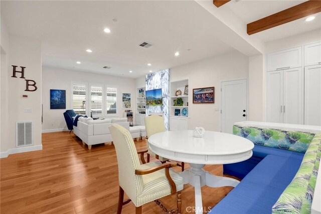 dining area featuring light hardwood / wood-style floors, built in shelves, and beam ceiling