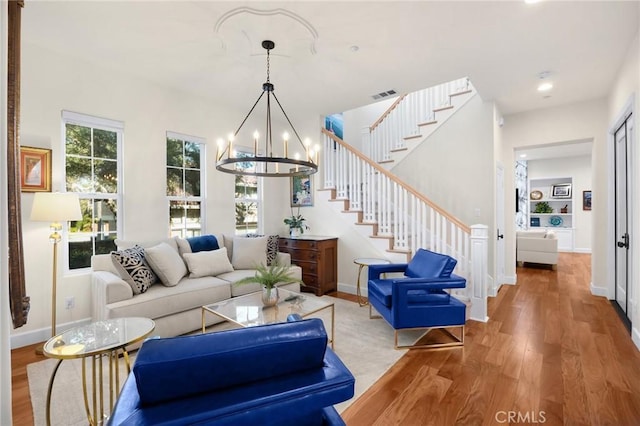 living room featuring hardwood / wood-style floors, built in features, and a chandelier