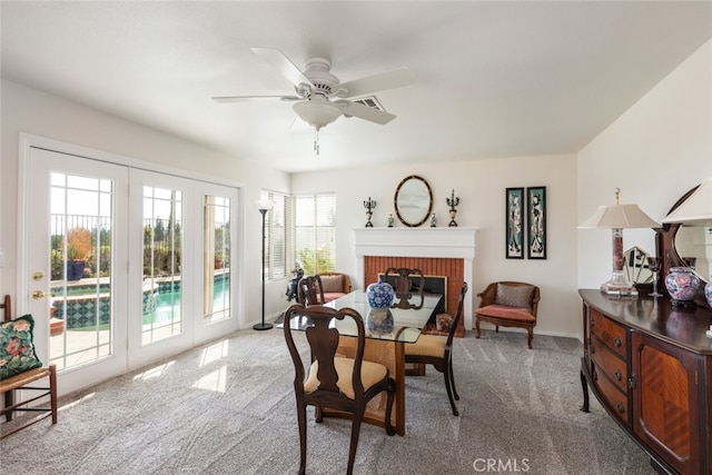 carpeted dining area with a brick fireplace and ceiling fan