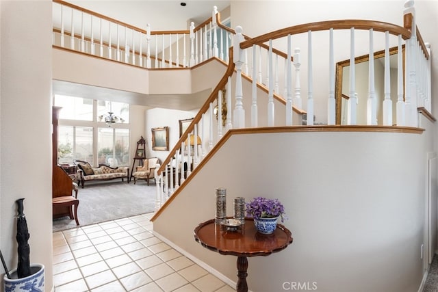 stairs featuring a towering ceiling, carpet, and a notable chandelier