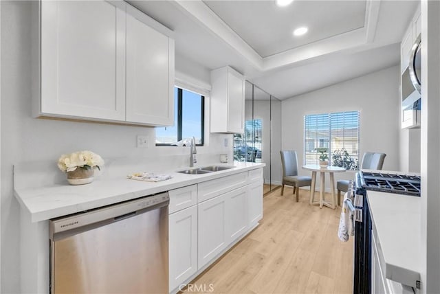 kitchen featuring light wood-type flooring, appliances with stainless steel finishes, white cabinetry, and sink