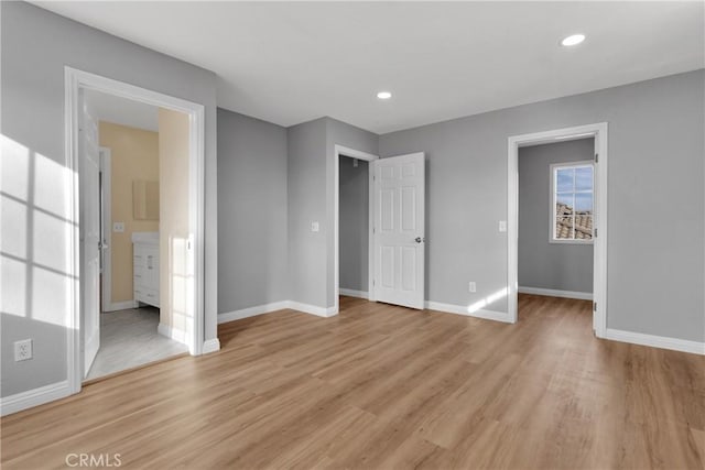 unfurnished bedroom featuring ensuite bath and light hardwood / wood-style flooring